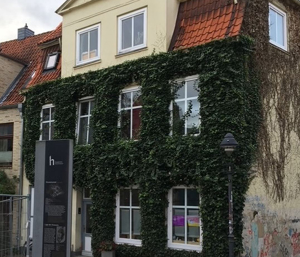 Das Haus vor der Sanierung mit blasser Fassade und weißen Fenstern