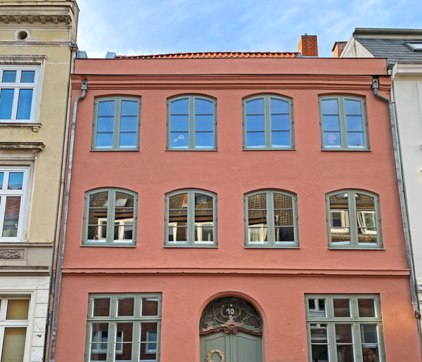 Wohnhaus in der Lübecker Altstadt nach der Sanierung: rote klassizistische Fassade mit rekonstruierten Sprossenfenstern